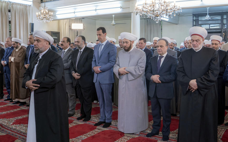 In this photo released by the Syrian official news agency SANA, Syrian President Bashar Assad, forth right, prays on the first day of the the Eid al-Adha, at Afram Mosque in Damascus, Syria, Sunday, Aug. 11, 2019. State news agency SANA showed Assad attending the payers early Sunday at Afram Mosque along with top officials including the prime minister and the country's grand mufti. (SANA via AP)