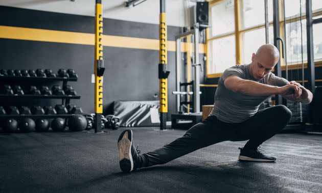 One man, fit male doing warm up exercise in gym.