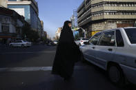 A veiled Iranian woman crosses Jomhouri-e-Eslami (Islamic Republic) St. in downtown Tehran, Iran, Monday, July 30, 2018. Iran's currency plummeted to a record low Monday, a week before the United States restores sanctions lifted under the unraveling nuclear deal, giving rise to fears of prolonged economic suffering and further civil unrest. (AP Photo/Vahid Salemi)