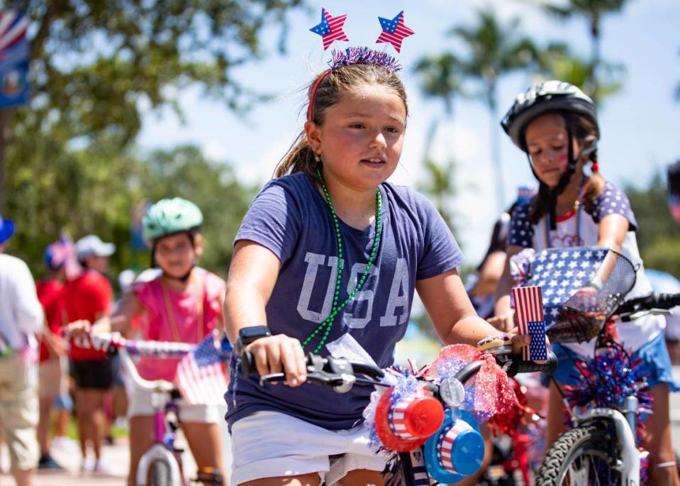 A young girl bikes down the road at an Independence Day parade on Thursday, July 4, 2024 in Key Biscayne, Fla. The Key Biscayne July Fourth parade is one of the oldest parades in South Florida, starting in 1959 and celebrating its 65th year.