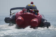 Tourists take a ride on an inflated Ultraman raft from a beach along the Taiwan Strait in Pingtan, eastern China's Fujian Province, Sunday, Aug. 7, 2022. Taiwan said Saturday that China's military drills appear to simulate an attack on the self-ruled island, after multiple Chinese warships and aircraft crossed the median line of the Taiwan Strait following U.S. House Speaker Nancy Pelosi's visit to Taipei that infuriated Beijing. (AP Photo/Ng Han Guan)