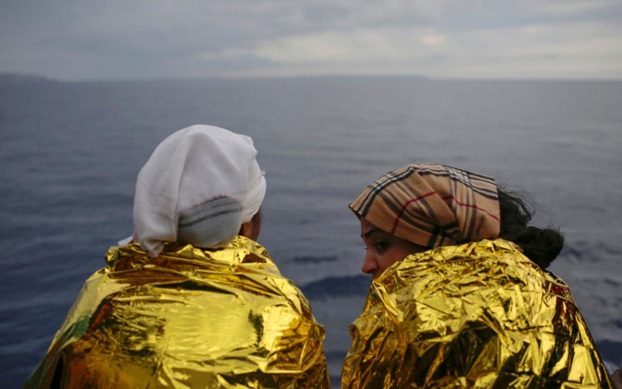 Two migrants look out from the deck of the Spanish NGO ProActiva Open Arms vessel as they wait to reach the Italian coast a day after being rescued off the Libyan coast on the Mediterranean Sea - AP