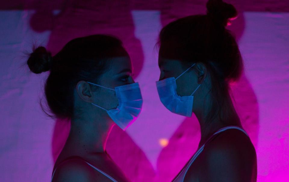 Photo of two women looking lovingly at each other wearing masks