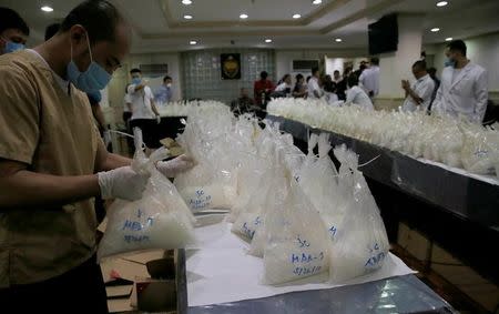 A chemist from the National Bureau of Investigation (NBI) inspects seized bags containing around 505 kilos of high-grade shabu drugs, which were confiscated last Saturday, after a news conference at NBI headquarters in Metro Manila, Philippines May 29, 2017. REUTERS/Romeo Ranoco