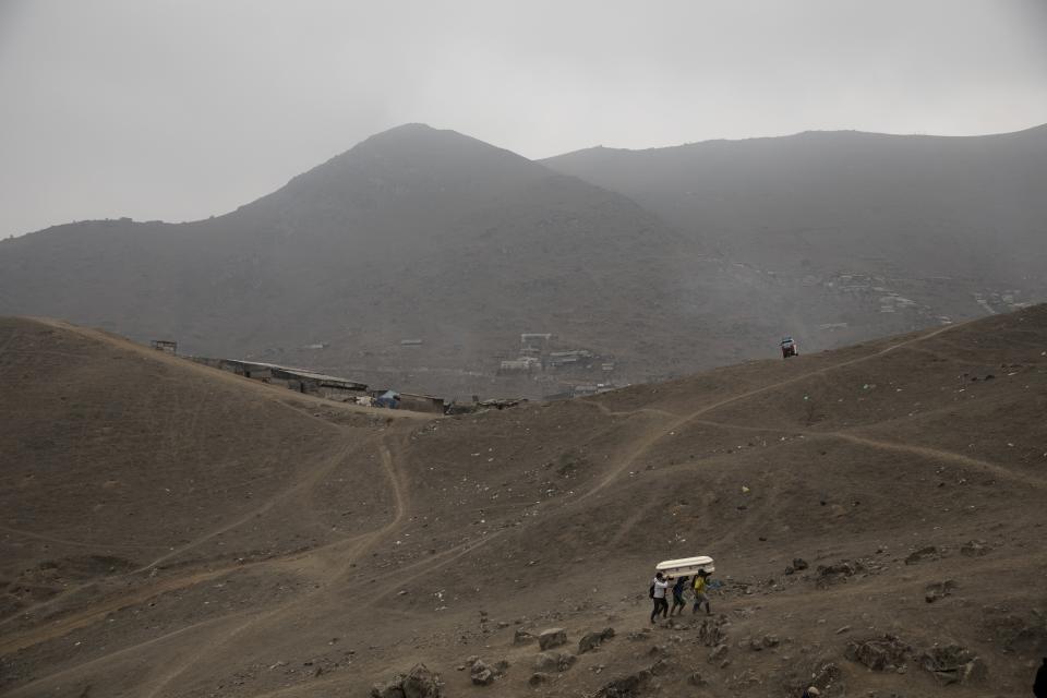 Cemetery workers carry the coffin that contain the remains of Apolonia Uanampa who died from the new coronavirus, in the Nueva Esperanza cemetery on the outskirts of Lima, Peru, Wednesday, May 27, 2020. (AP Photo/Rodrigo Abd)