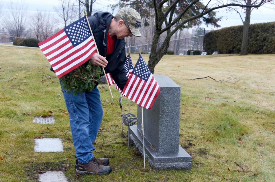 Craig Griffore of Levering places an American flag at a veteran's grave on Saturday, Dec. 16, 2023 at Greenwood Cemetery during the annual Wreaths Across America event. In the Jewish section of the cemetery, volunteers placed flags instead of wreaths.