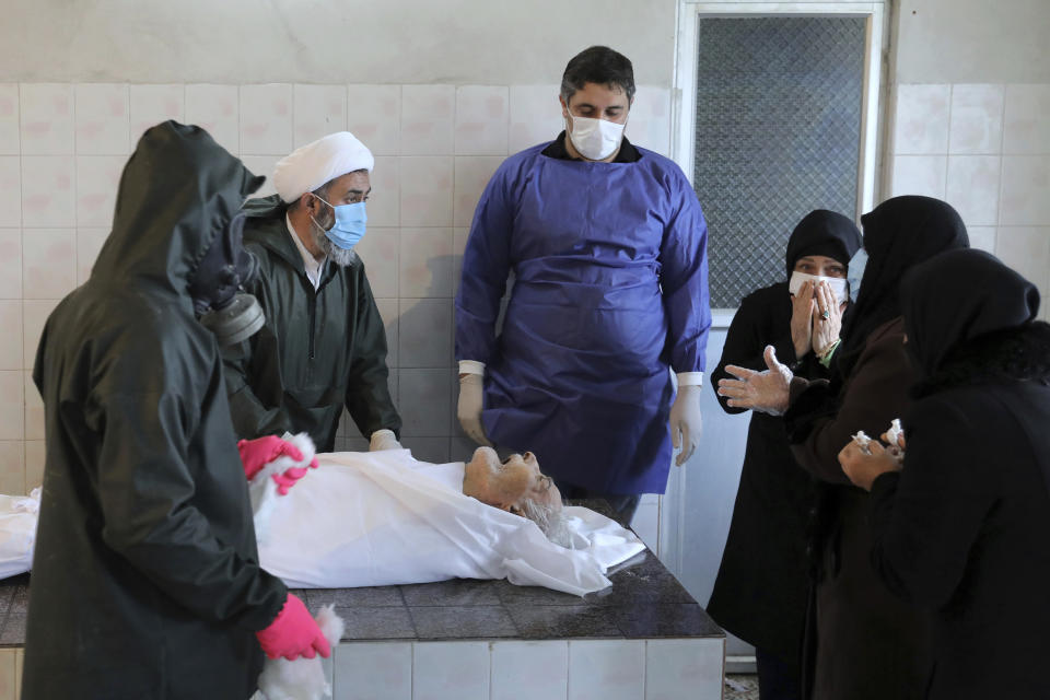 Relatives mourn over the body of Hadi Hamekasi, 85, who died from COVID-19 at a cemetery in the Chaali village on the outskirts of the city of Ghaemshahr, in northern Iran, Thursday, Dec. 17, 2020. (AP Photo/Ebrahim Noroozi)