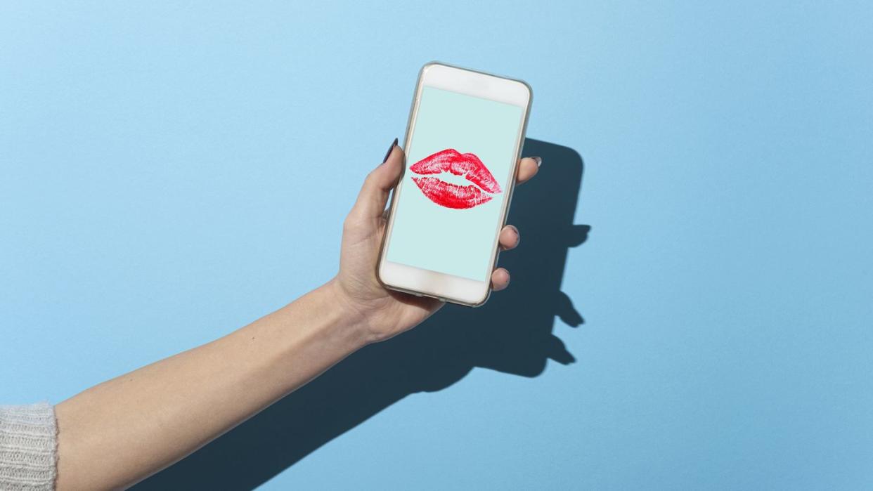 woman's hand shows her smartphone with lipstick kiss