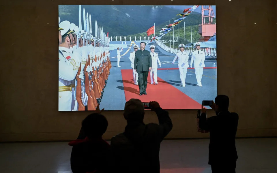 A film is screened at a museum which shows Xi Jinping walking on a navy shandong aircraft carrier surrounded by members of the People's Liberation Army who are saluting the president