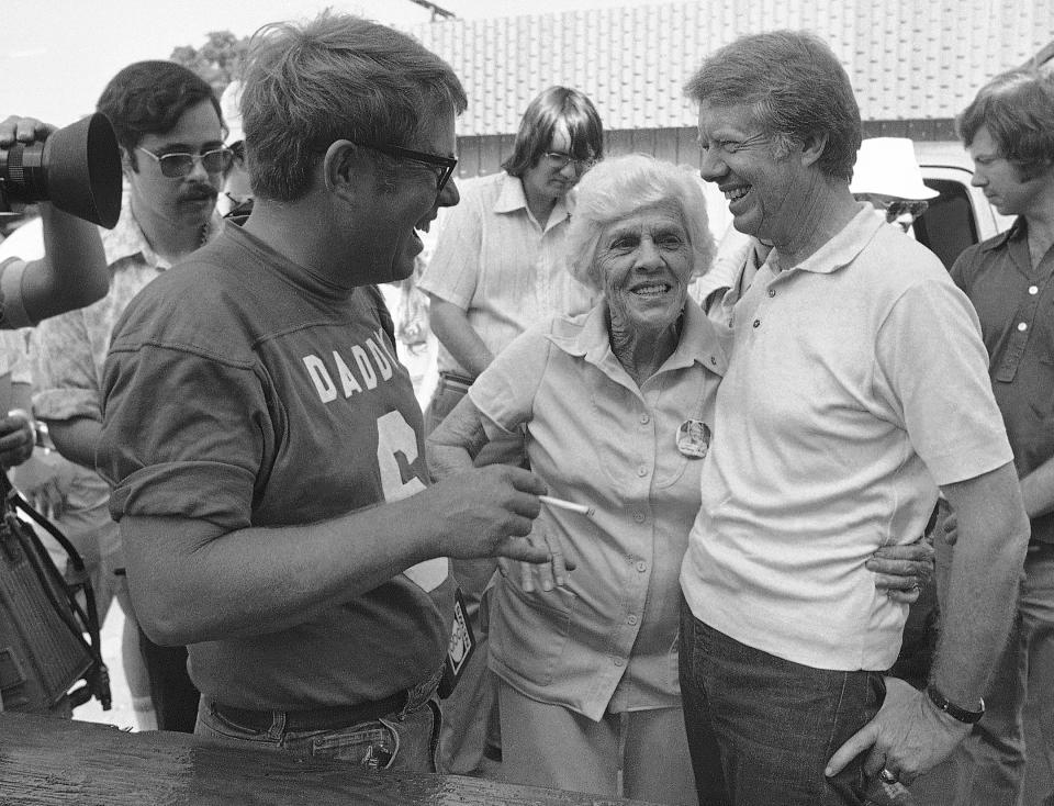 FILE - Lillian Carter is flanked by her sons Jimmy, right, and Billy as she met them down at Billy's gas station, where the Carters and neighbors cleaned fish prior to a town cookout, June 26, 1976. When Jimmy Carter stepped onto the national stage, he brought those closest to him along, introducing Americans to a colorful Georgia family that helped shape the 39th president’s public life and now, generations later, is rallying around him for the private final chapter of his 98 years. (AP Photo/Mark Foley, File)