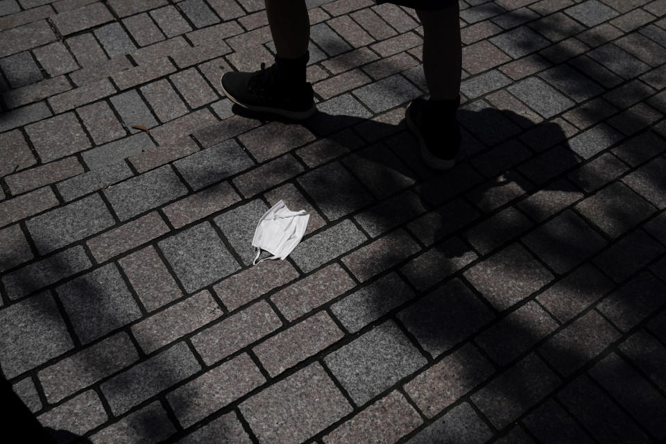 A pedestrian walks past a face mask discarded on the street during the 2020 Summer Olympics, Saturday, July 24, 2021, in Tokyo. (AP Photo/Jae C. Hong)