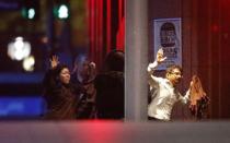 Hostages run past a police officer (C) near Lindt Cafe in Martin Place in central Sydney December 16, 2014. REUTERS/Jason Reed