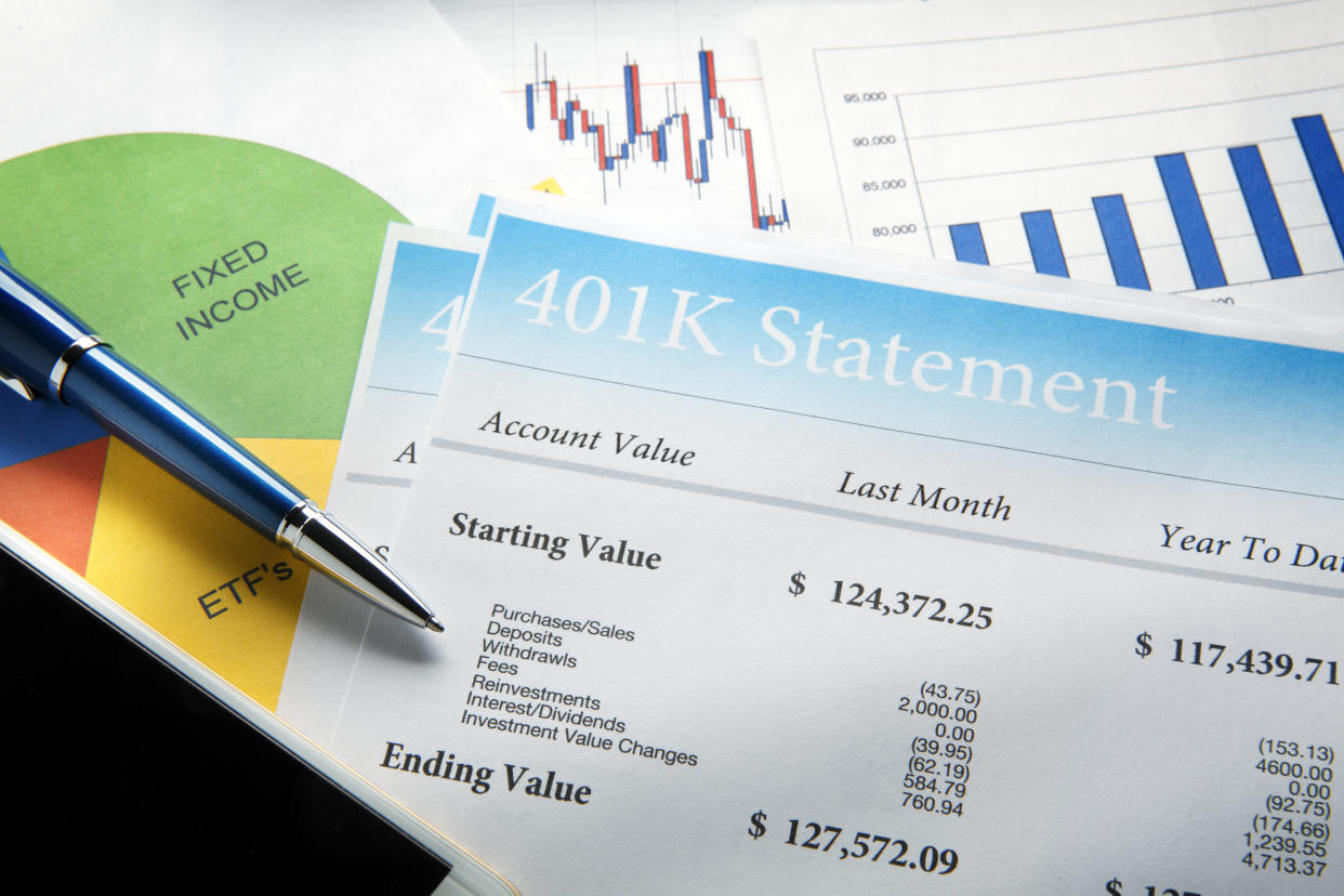 A blue ballpoint pen and a mobile phone rest on top of a 401k retirement statement and a pie chart that shows retirement account asset allocation.