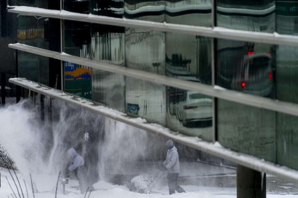 Men use snow blowers to clear a sidewalk in downtown Des Moines, Iowa, Saturday, Jan. 13, 2024. (AP Photo/Andrew Harnik)