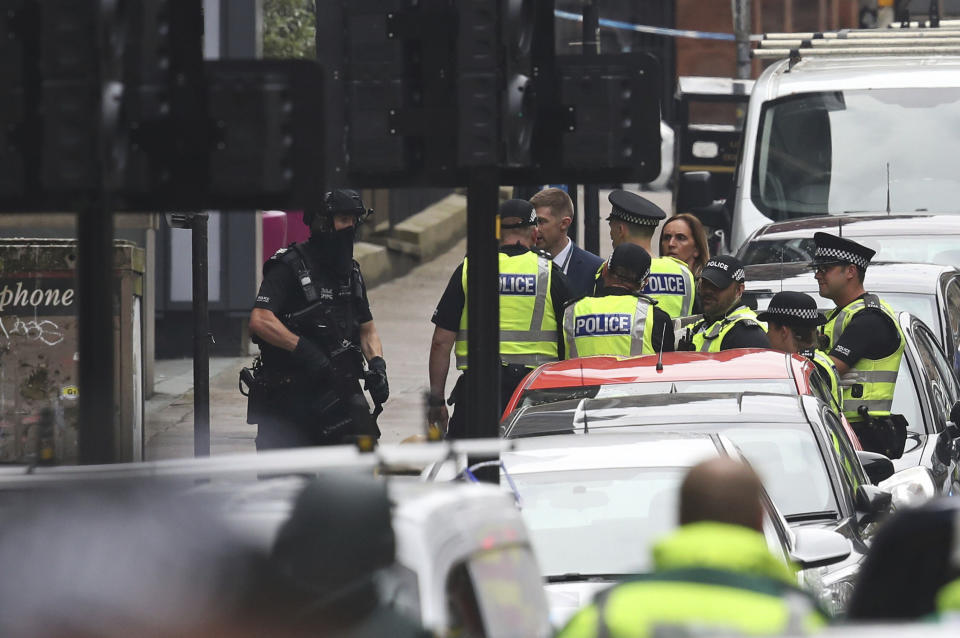 Armed police at the scene of an incident in Glasgow, Scotland, Friday June 26, 2020. Scottish police say the individual shot by armed police during an incident in Glasgow has died and that six other people including a police officer are in hospital being treated for their injuries. (Andrew Milligan/PA via AP)