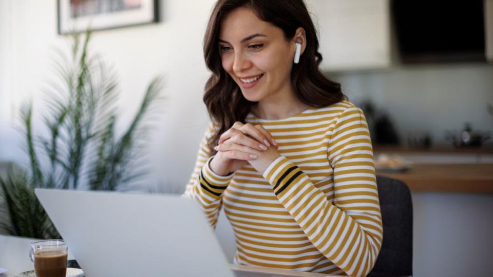 Surveys for money: Young smiling woman with bluetooth headphones having video call at home -