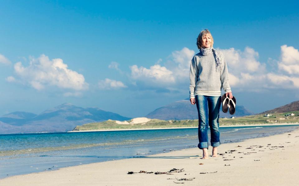 Carefree adult woman walking on the sands of Luskentyre beach on Harris in the Outer Hebrides of Scotland - lucentius