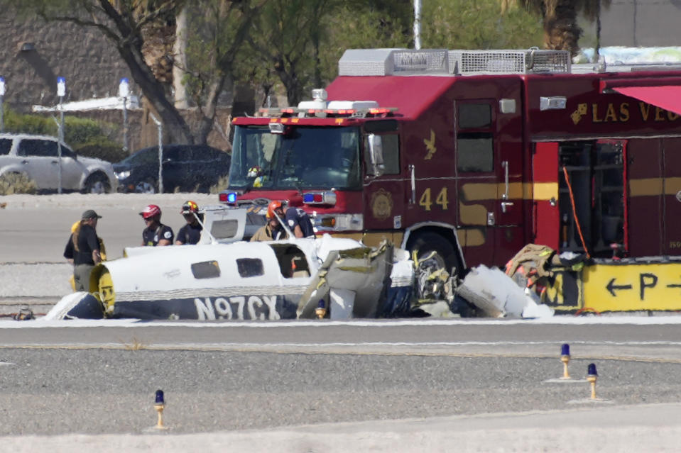 Officials investigate the wreckage of a plane at the site of a fatal crash at the North Las Vegas Airport, Sunday, July 17, 2022, in North Las Vegas, Nev. Authorities say several people are dead after two small planes collided at North Las Vegas Airport. (AP Photo/John Locher)