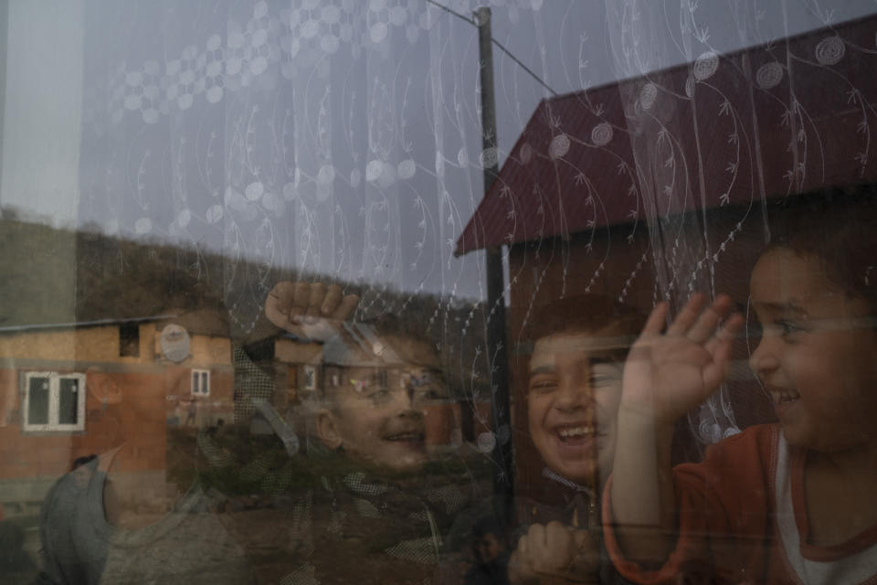 In this Nov. 14, 2018, photo, homes are reflected off the window of Monika Krcova's house as her grandchildren play inside at the Podhorany village near Kezmarok, Slovakia. Krcova did not want to follow the official guidelines and remain in the hospital for four days after her third baby’s birth. And so she escaped. Slovakia’s Ministry of Health recommends four-day stays for mothers and babies, regardless of their health. Many hospitals seeking insurance reimbursements have turned that into a mandate. (AP Photo/Felipe Dana)