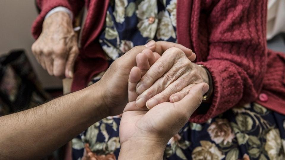 Care worker holding elderly womans hand