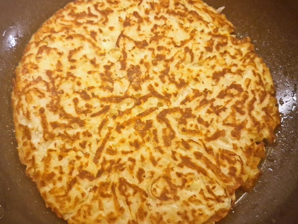 hash browns cooking in a frying pan