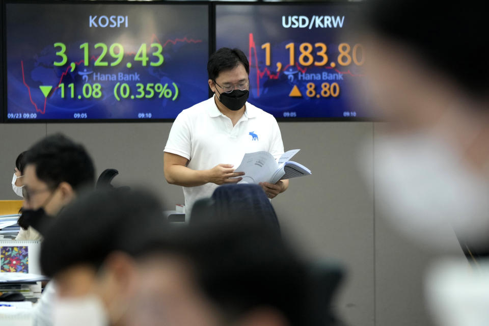 A currency trader passes by screens showing the Korea Composite Stock Price Index (KOSPI), left, and the exchange rate of South Korean won against the U.S. dollar at the foreign exchange dealing room of the KEB Hana Bank headquarters in Seoul, South Korea, Thursday, Sept. 23, 2021. Asian shares were mostly higher on Thursday after the Federal Reserve signaled it may begin easing its extraordinary support measures for the economy later this year.(AP Photo/Ahn Young-joon)