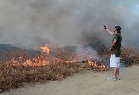 A spectator films the La Tuna Canyon fire over Burbank. REUTERS/ Kyle Grillot