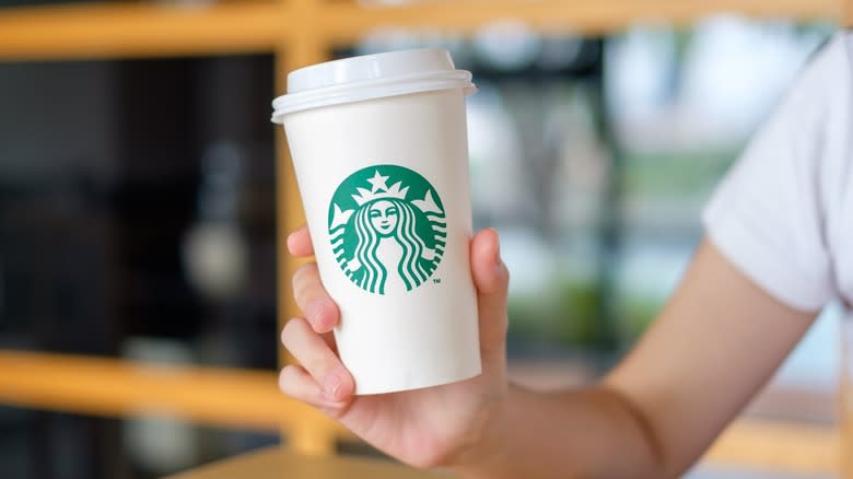 Hand holding white Starbucks cup