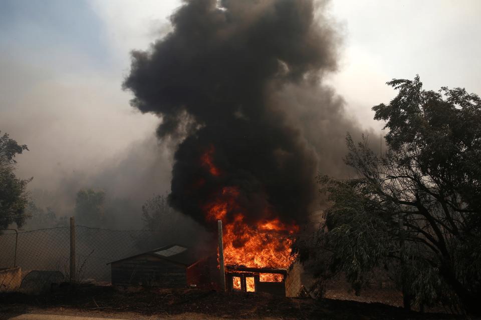 A house caught ablaze during a wildfire at the Lagonisi area (EPA/YANNIS KOLESIDIS)