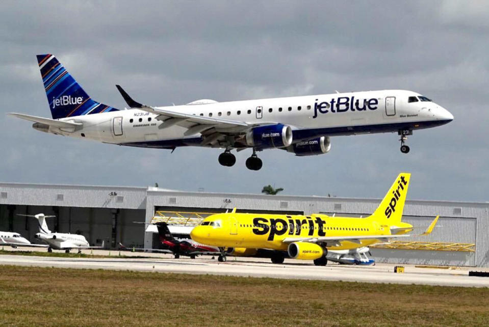 A JetBlue Airways plane passes a Spirit Airlines jet as it lands at Fort Lauderdale Hollywood International Airport. (Joe Cavaretta/Sun Sentinel/Tribune News Service via Getty Images)