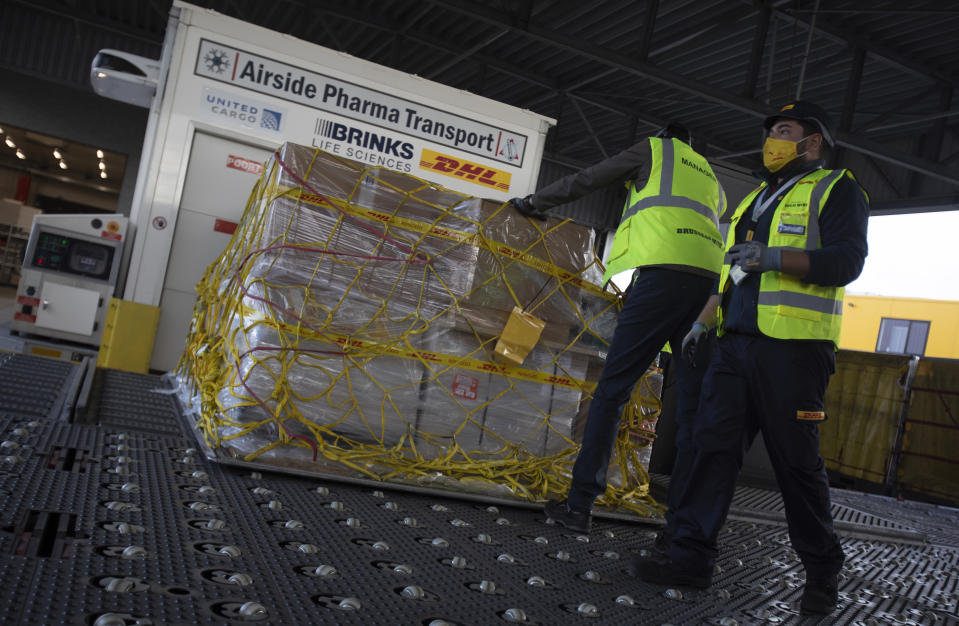 Cargo workers move a palette of cool boxes and other items into a pharma transport container during a demonstration on the handling and logistics of vaccines and medicines at the DHL cargo warehouse in Steenokkerzeel, Belgium, Tuesday, Dec. 1, 2020. European Commission President Ursula von der Leyen said Tuesday that member states have started working on their vaccination plans and on the logistics for the delivery of tens of millions of doses across the 27-nation bloc. Safely delivering COVID-19 vaccines, once approval has been made, will be the mission of the century for the global air cargo industry. (AP Photo/Virginia Mayo)