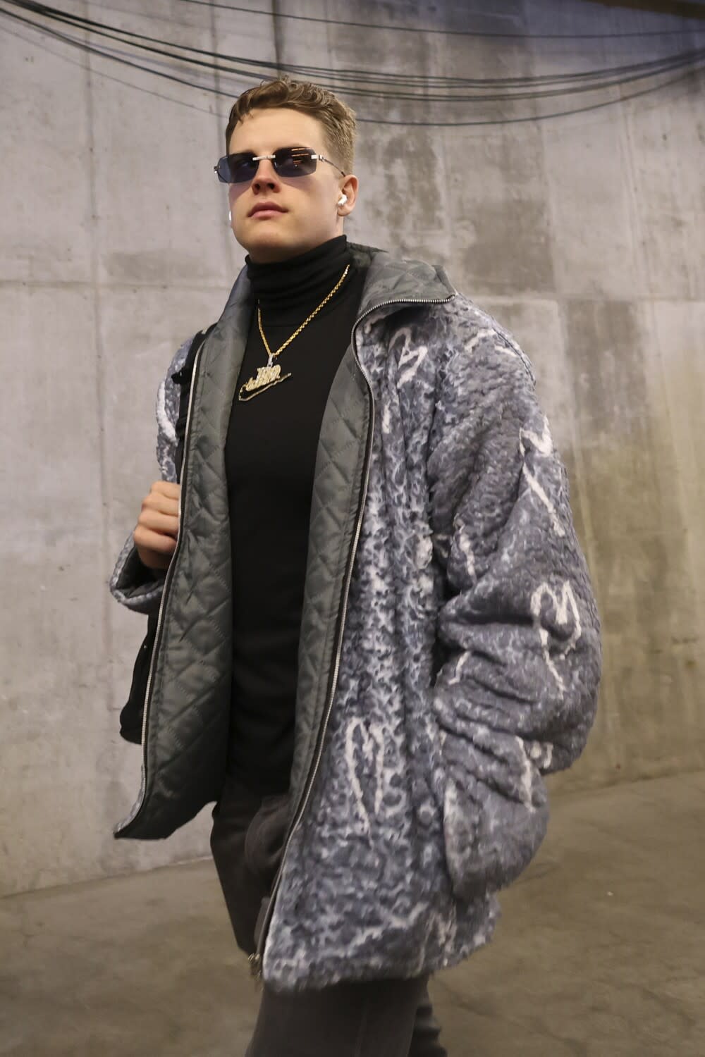 Joe Burrow walks down a stadium tunnel wearing a coat decorated with hearts before the AFC championship game