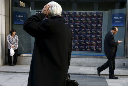 A man looks at an electronic board showing market indices outside a brokerage in Tokyo, Japan, March 2, 2016. REUTERS/Thomas Peter