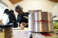 Chief coordinator Glenda Andrew, centre and volunteer Dave Williams prepare West Indian meals with members of the Preston Windrush Covid Response team, at the Xaverian Sanctuary, in Preston, England, Friday Feb. 19, 2021. Once a week they distribute meals to people in Preston and surrounding communities in northwestern England that have recorded some of the U.K.’s highest coronavirus infection rates. The meal program grew out of Andrew’s work with Preston Windrush Generation & Descendants, a group organized to fight for the rights of early immigrants from the Caribbean and other former British colonies who found themselves threatened with deportation in recent years. (AP Photo/Jon Super)