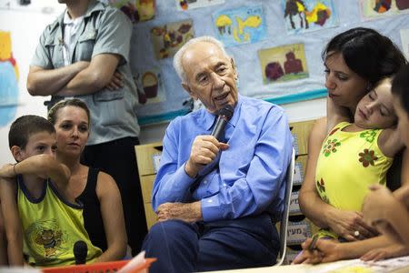 Israel's President Shimon Peres (C) speaks as he sits next to children during his visit to a kindergarten protected against bombs in Kibbutz Zikim, just north of the Gaza Strip July 17, 2014. REUTERS/Amir Cohen