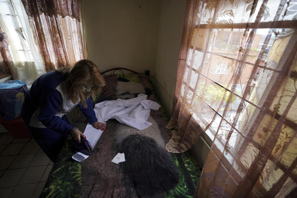 Yessica Candia irons a shirt for her son Javier Vega in preparation for his marriage to his fiancé in a mass wedding ceremony organized by city authorities as part of the LGBT pride month celebrations, in Mexico City, Friday, June 24, 2022. (AP Photo/Fernando Llano)