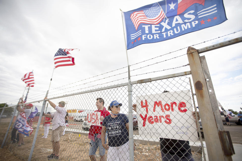 Standing at the fence, supporters of President Donald Trump display flags and signs as they wait for Air Force One to land Wednesday afternoon July 29, 2020 at Midland International Air and Space Port in Midland Texas. (Ben Powell/Odessa American via AP)