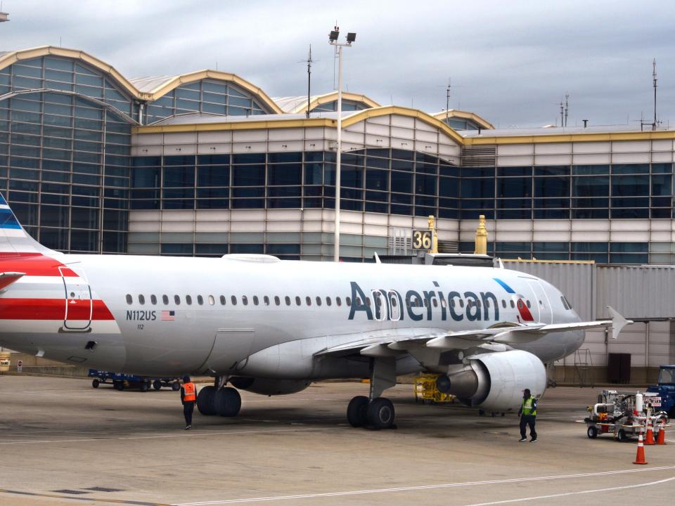 An American Airlines Airbus A320 passenger plane is serviced at an airport gate.