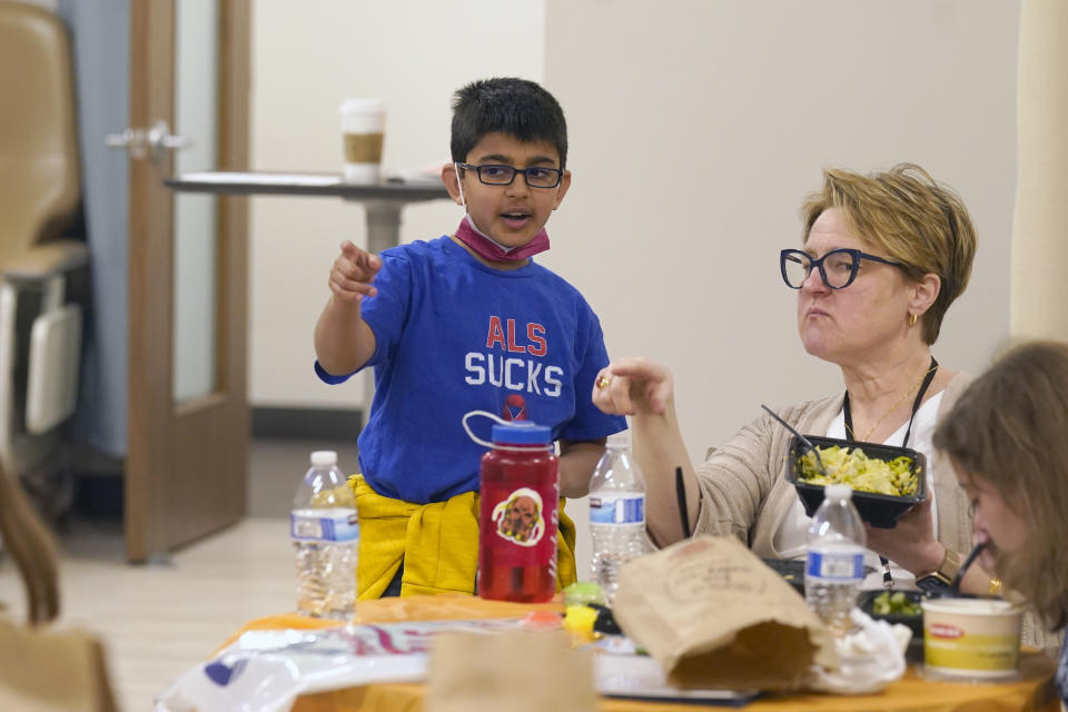 Melinda Kavanaugh, right, a University of Wisconsin-Milwaukee social work professor, listens to Ronan Kotiya, 11, as the take a lunch break during a clinic for young caregivers of ALS family members in Dallas, Texas, Saturday, April 9, 2022. Kavanaugh thinks as many as 10 million children are involved in caregiving in the U.S. and says youth caregiving will grow as the U.S. population ages and chronic health problems like diabetes become more common. She and other researchers say young caregivers provide crucial help to their families, and they need more support. (AP Photo/LM Otero)