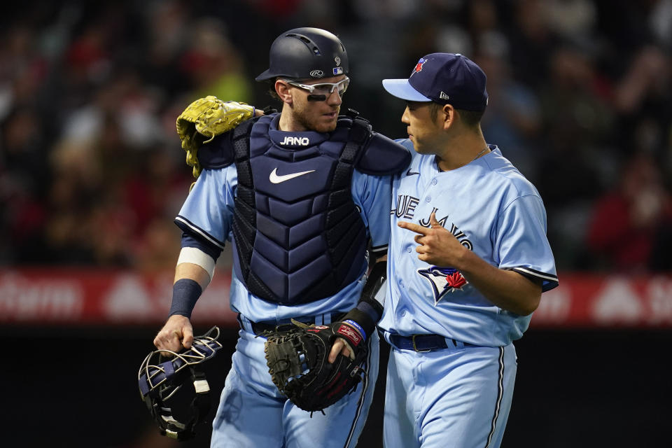 Toronto Blue Jays catcher Danny Jansen, left, talks with starting pitcher Yusei Kikuchi as they return to the dugout after the second inning of a baseball game against the Los Angeles Angels in Anaheim, Calif., Saturday, May 28, 2022. (AP Photo/Ashley Landis)