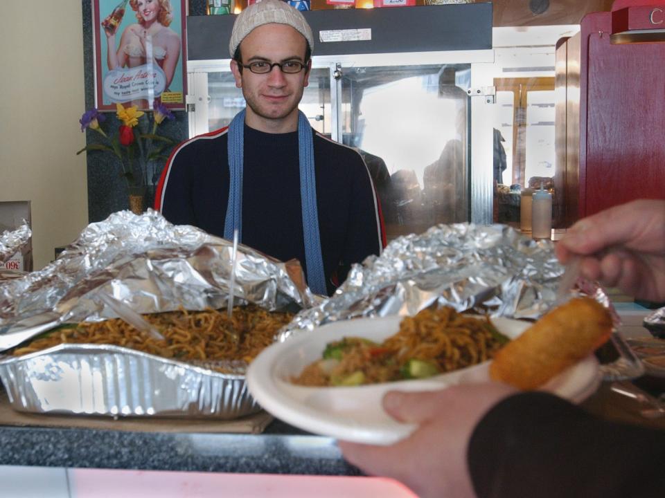 Adam Sekuler, programmer for the Bell Auditorium, keeps the holiday Chinese buffet running smoothly at the Oak Street Cinema