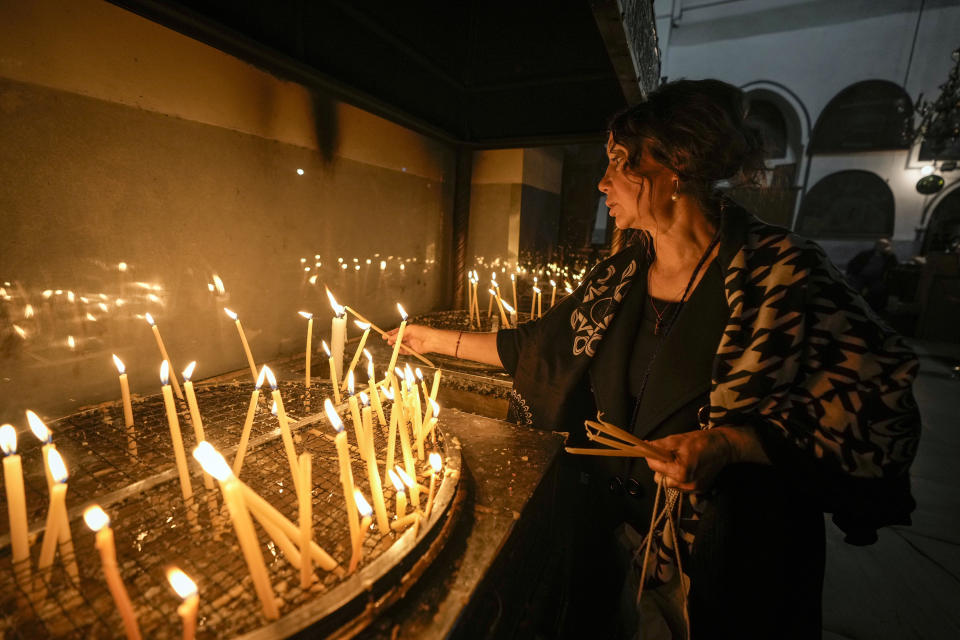 A woman lights candles inside the Church of the Nativity, traditionally believed to be the birthplace of Jesus Christ, in the West Bank town of Bethlehem,Saturday , Dec. 24, 2022. (AP Photo/Majdi Mohammed)