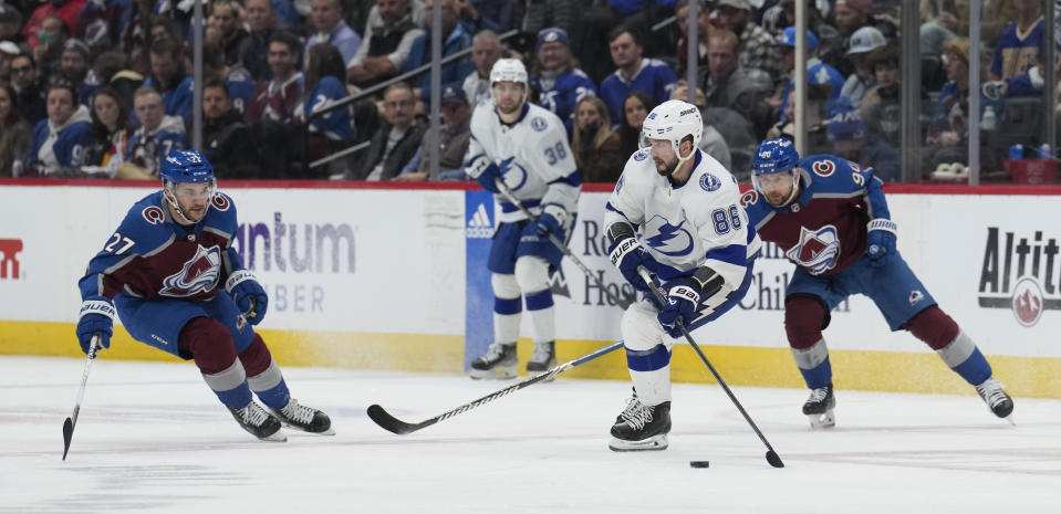 Tampa Bay Lightning right wing Nikita Kucherov, center, looks to pass the puck as Colorado Avalanche left wings Jonathan Drouin, left, and Tomas Tatar defend in the third period of an NHL hockey game Monday, Nov. 27, 2023, in Denver. (AP Photo/David Zalubowski)