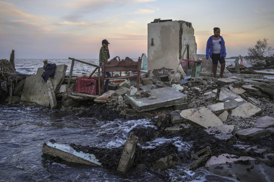 FILE - Yahir Mayoral and Emily Camacho walk amid the rubble of their grandmother's home, destroyed by flooding driven by a sea-level rise in their coastal community of El Bosque, in the state of Tabasco, Mexico, Nov. 30, 2023. Driven by climate change, sea-level rise and increasingly ferocious storms are eroding thousands of miles of Mexico's coastline facing both the Gulf and the Pacific Ocean. (AP Photo/Felix Marquez, File)