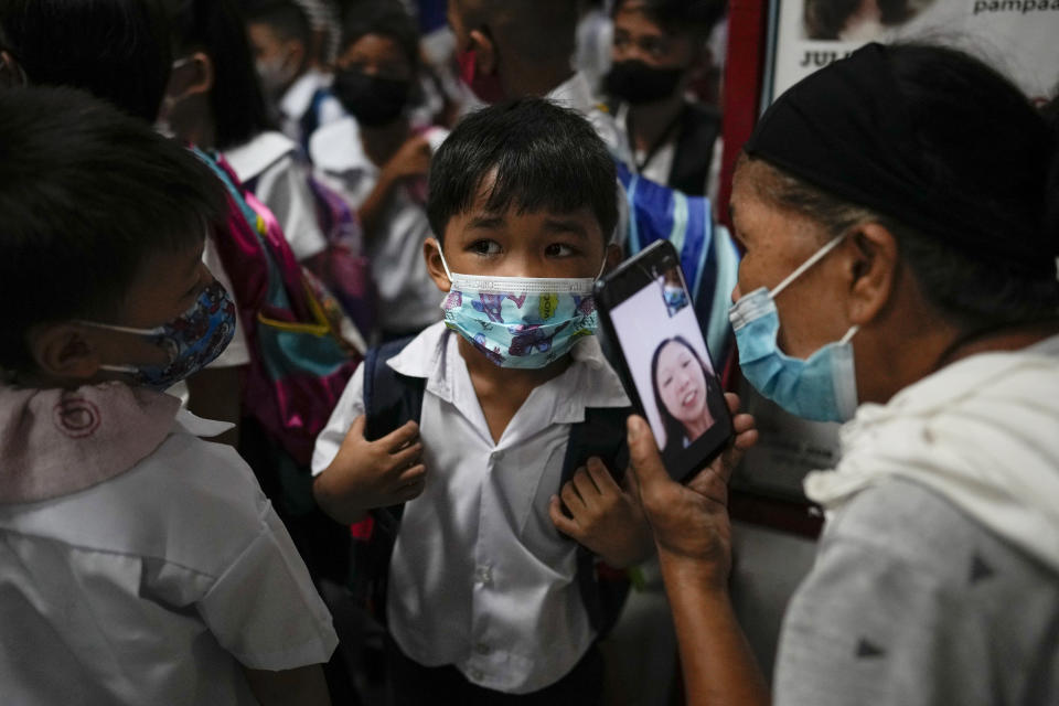 A boy talks to his mother from a smartphone during the opening of classes at the San Juan Elementary School in metro Manila, Philippines on Monday, Aug. 22, 2022. Millions of students wearing face masks streamed back to grade and high schools across the Philippines Monday in their first in-person classes after two years of coronavirus lockdowns that are feared to have worsened one of the world's most alarming illiteracy rates among children. (AP Photo/Aaron Favila)