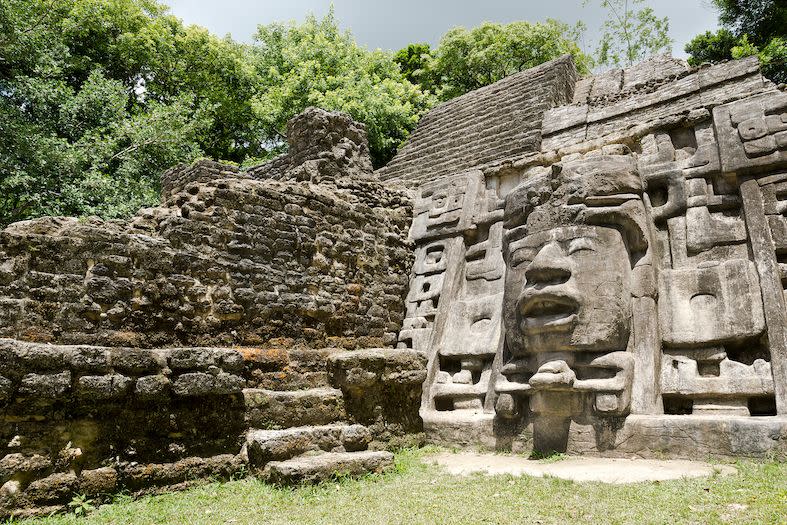 an ancient stone temple in belize with a face carved into the rock