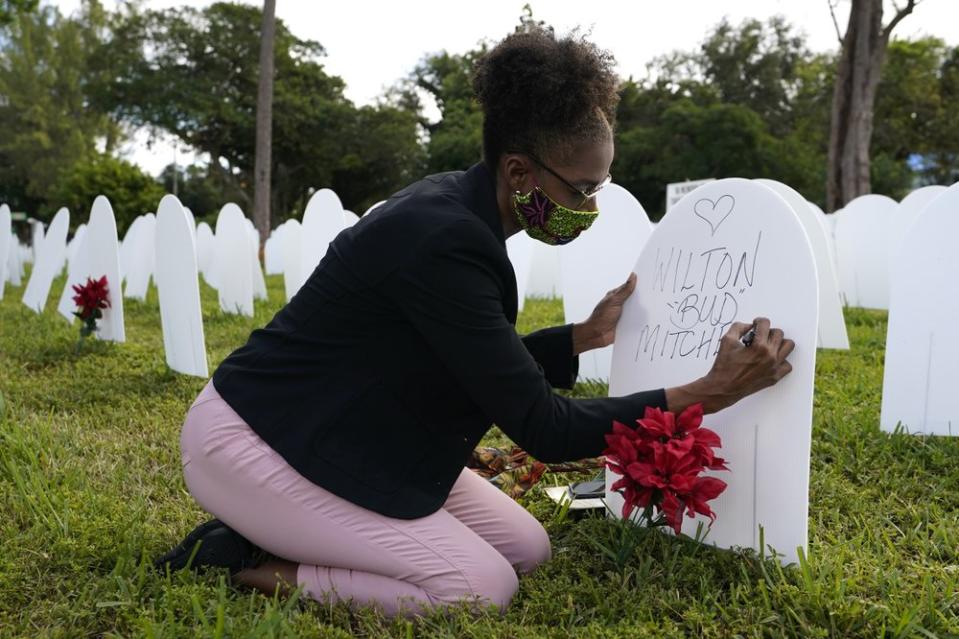 Rachel Moore writes a tribute to her cousin Wilton “Bud” Mitchell who died of COVID-19 at a symbolic cemetery created to remember and honor lives lost to COVID-19, in the Liberty City neighborhood of Miami. (AP Photo/Lynne Sladky, File)
