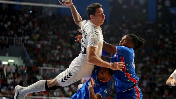 Ahmed Al Ahmer mid-air with the handball as Cape Verde defenders try to stop him.