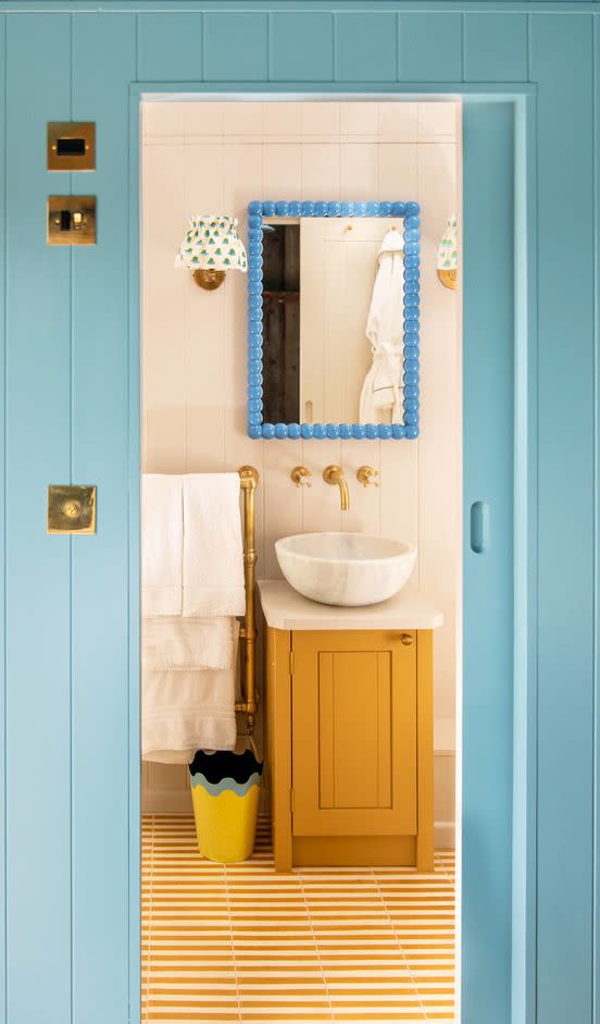 bathroom with shiny blue lacquered mirror and yellow and white striped tile