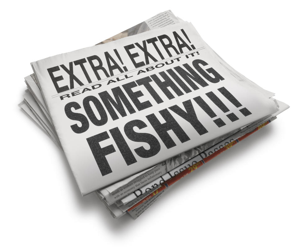 A stack of newspapers with the top headline reading "EXTRA! EXTRA! READ ALL ABOUT IT! SOMETHING FISHY!!!"